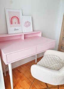 Stylowa aranżacja pokoju dziecka z pastelowym różowym biurkiem, meblami handmade i wygodnym fotelem.