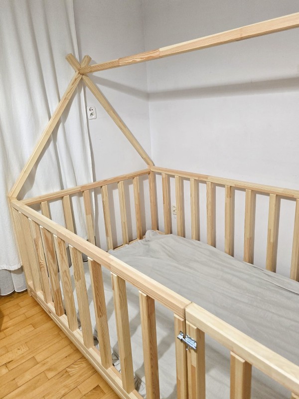 Piękne łóżko podłogowe typu tipi w dziecięcym pokoju. Niska konstrukcja pozwala na łatwe wchodzenie, a dzięki barierkom mebel pełni funkcję bezpiecznego kojca dla maluszka.