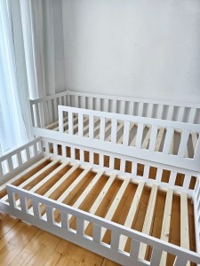 Białe łóżko piętrowe z wysuniętą dolną szufladą do spania dla dwójki dzieci