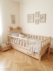 Drewniane łóżko dziecięce z barierkami i wysuwaną szufladą do spania w pokoju dziecięcym